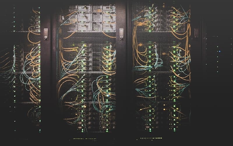 Server racks carrying dense bundles of orange and yellow patch cables routed through cable management arms